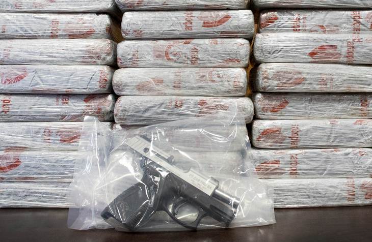 Esta fotografía muestra un arma de fuego y 70 kilogramos (154 libras) de heroína con un valor de al menos 50 millones de dólares durante una conferencia de prensa del departamento antidrogas de Estados Unidos (DEA, por sus siglas en inglés), el martes 19 de mayo de 2015 en Nueva York. La DEA señaló que este es el decomiso de heroína más grande en la historia del estado de Nueva York. Las autoridades señalaron el martes que la mayoría de las drogas fueron encontradas en una camioneta en el distrito del Bronx luego de una investigación de escuchas telefónicas. (Foto AP/Mark Lennihan)